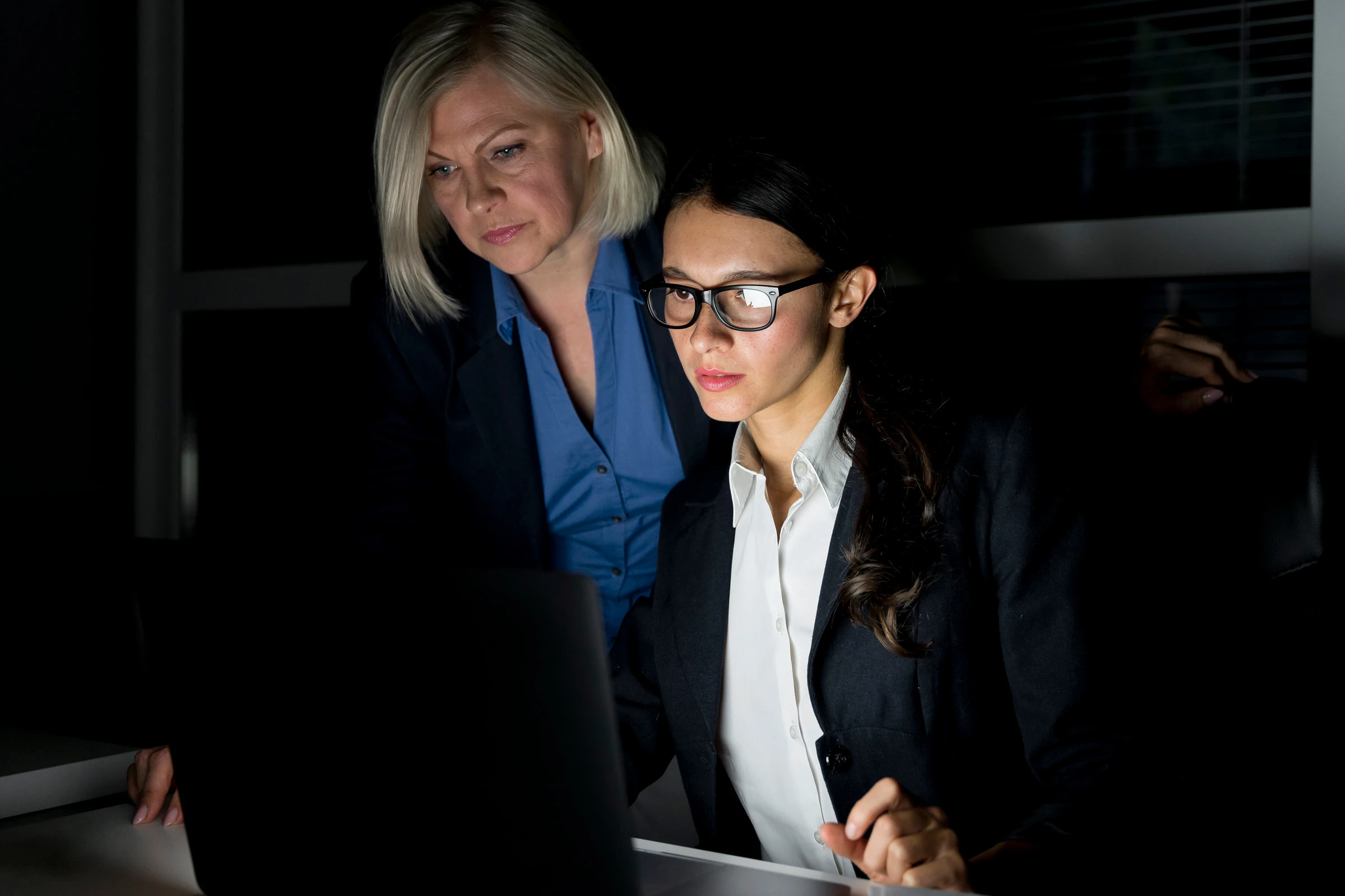 Duas profissionais analisam uma tela de computador juntas em um escritório